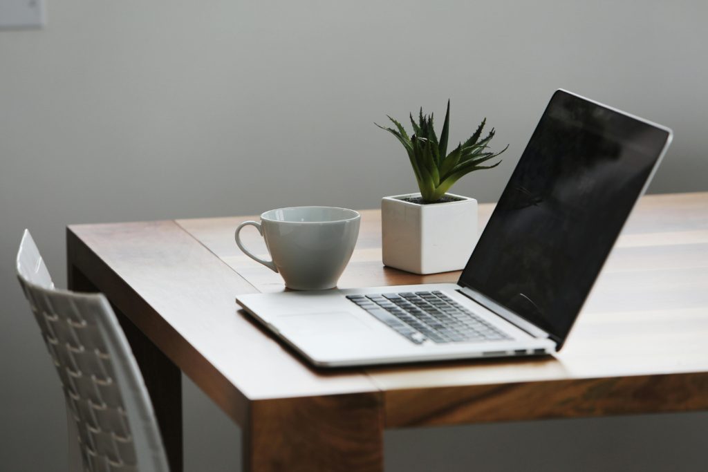 Silver Laptop Computer Next to Ceramic Cup